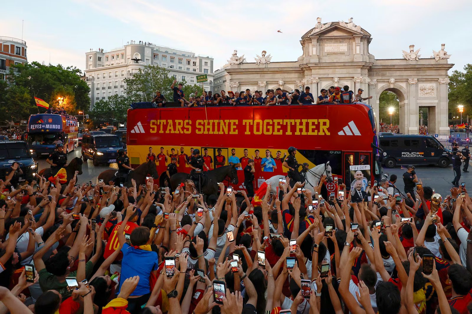 Aficionados celebran junto al autobús de la selección española frente a la Puerta de Alcalá de Madrid